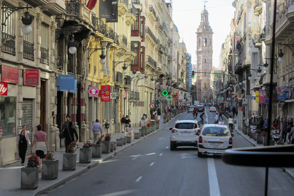 Calle del centro de Valencia con edificios de viviendas y la torre de Santa Catalina al fondo